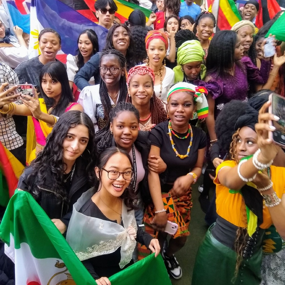 Students in national costumes with flags on concourse